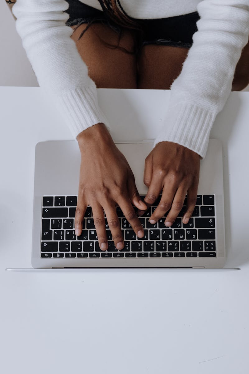 Overhead shot of a woman typing on a laptop in a modern home office setting.